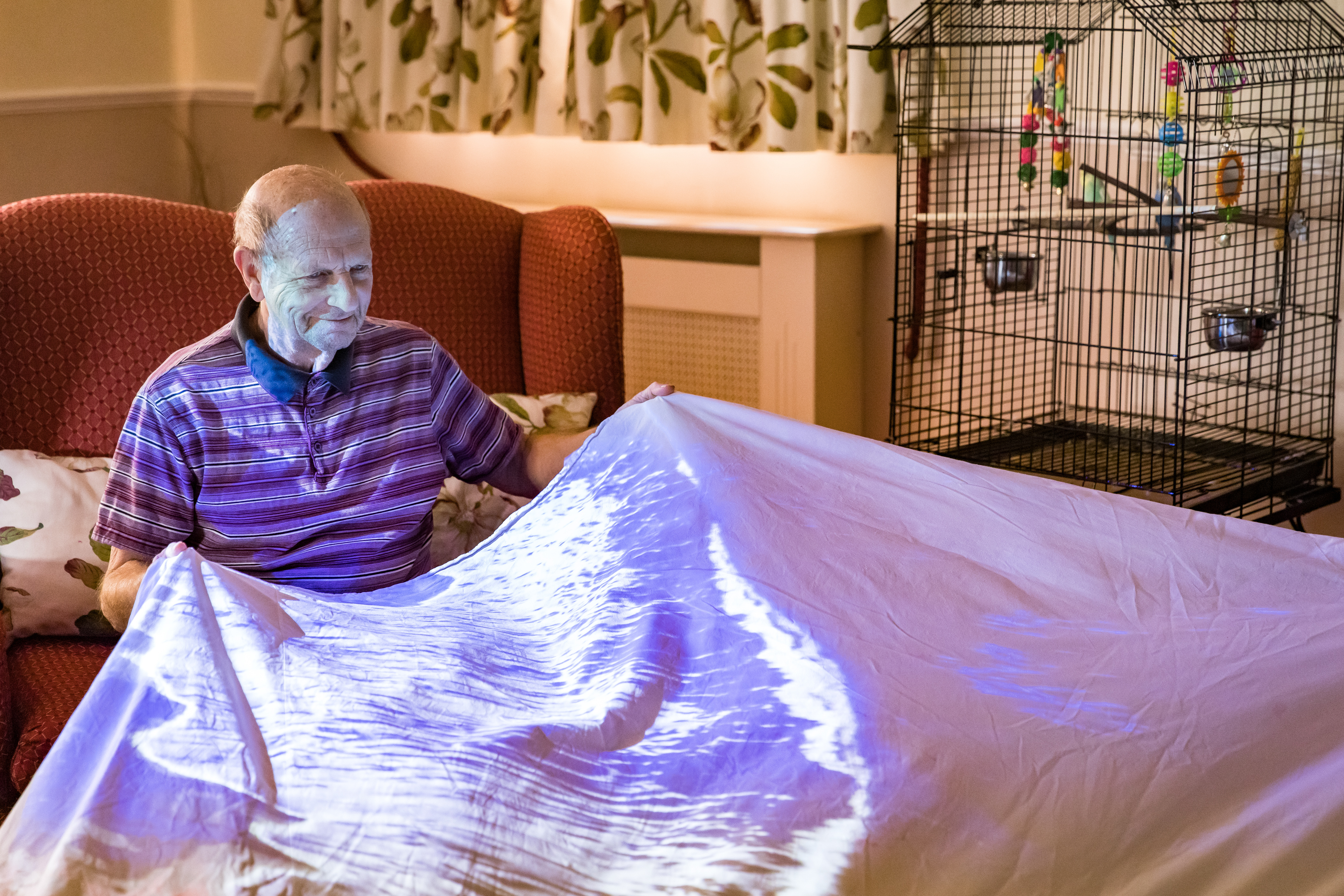 Elderly male holding up a bed sheet