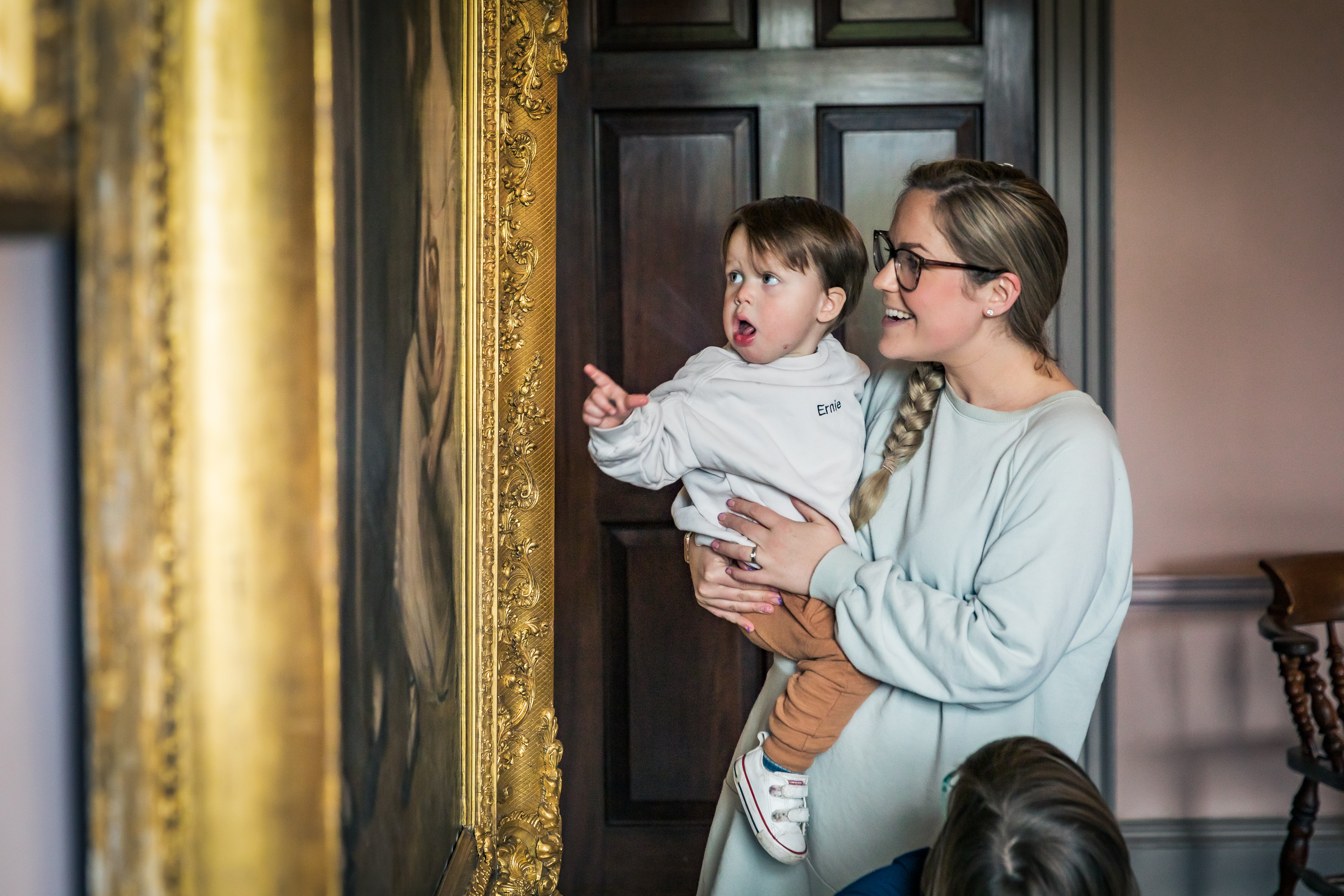 Woman holding a child whilst looking at a painting