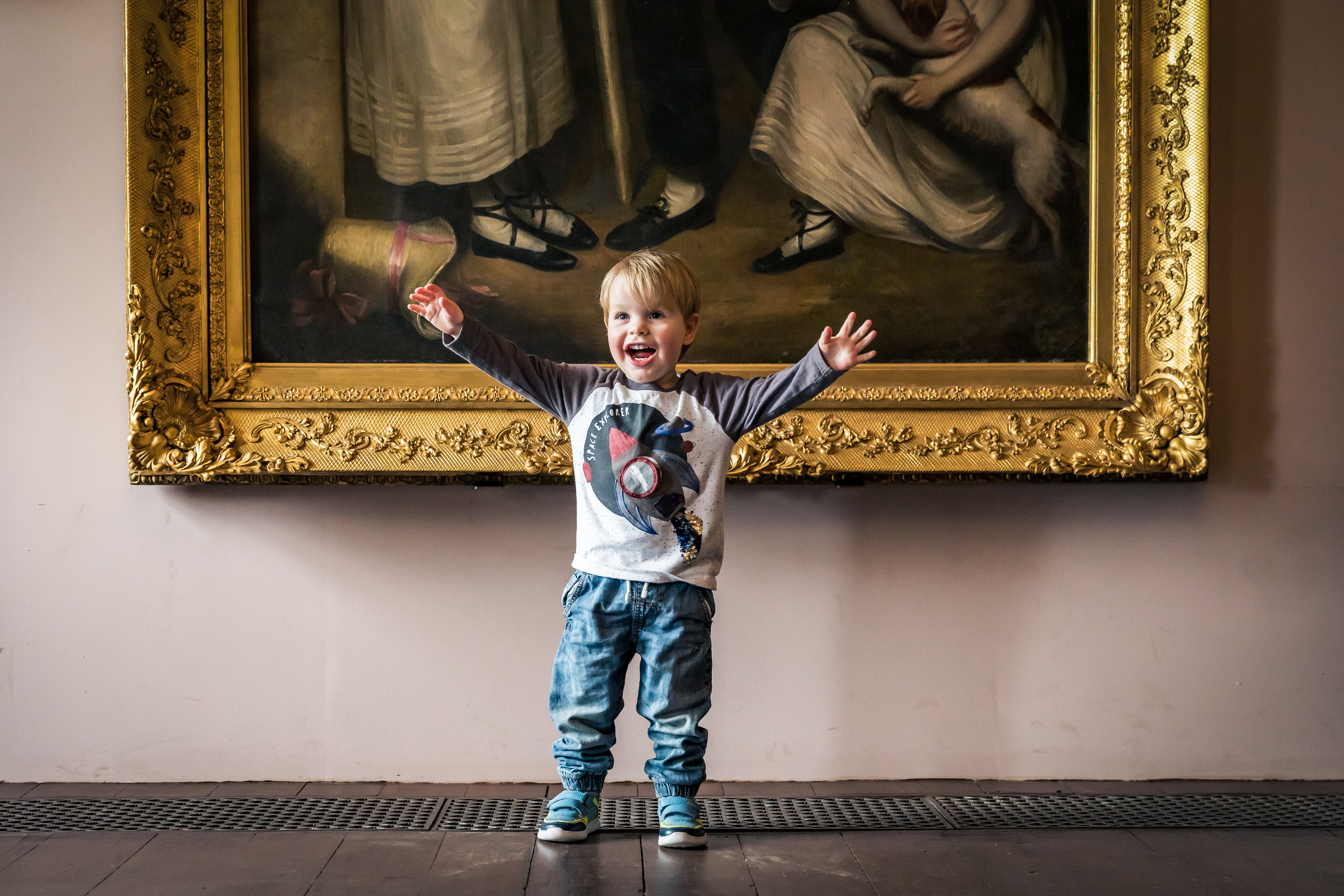 Child standing in front of a large painting