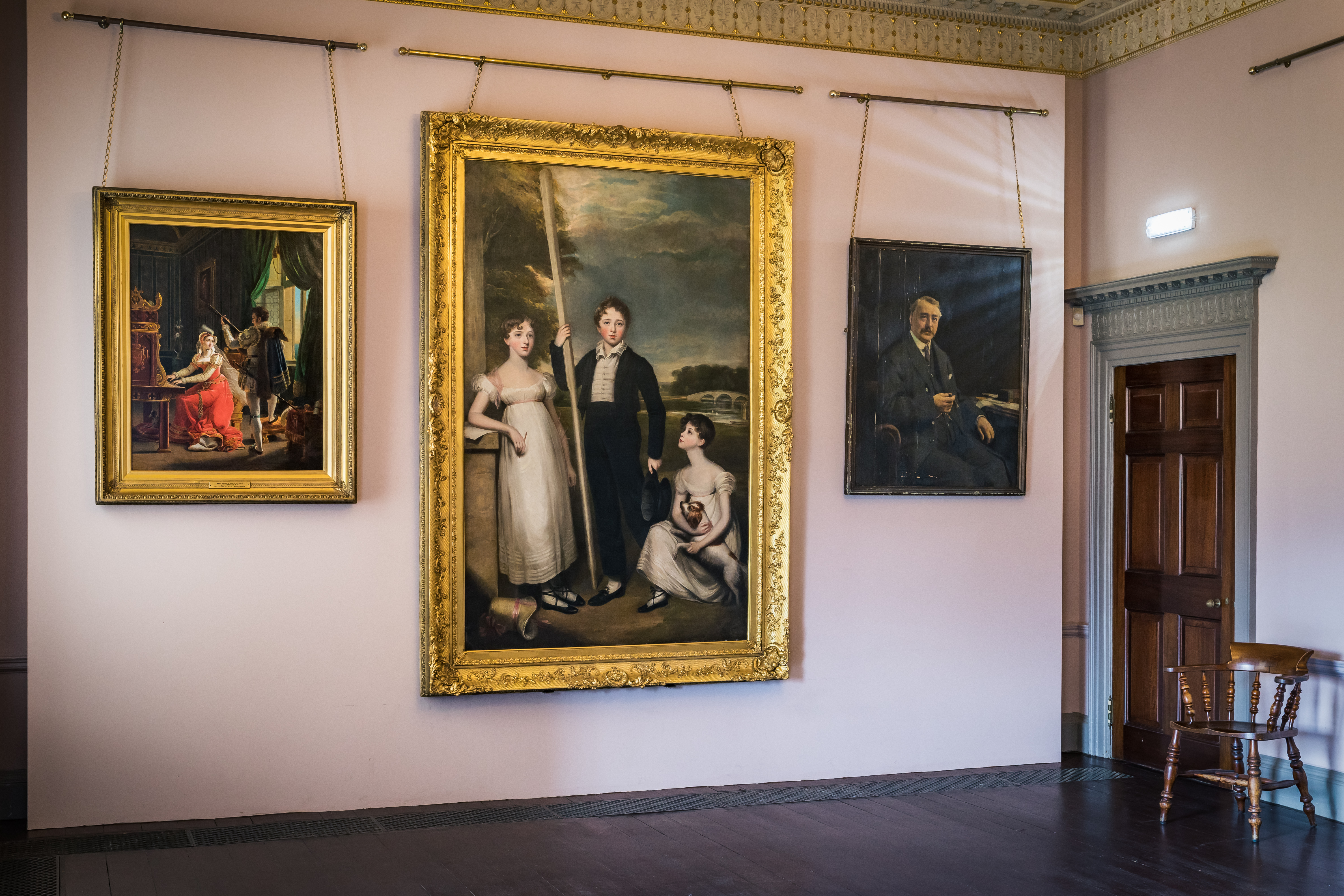 three paintings hung on a wall in gold frames