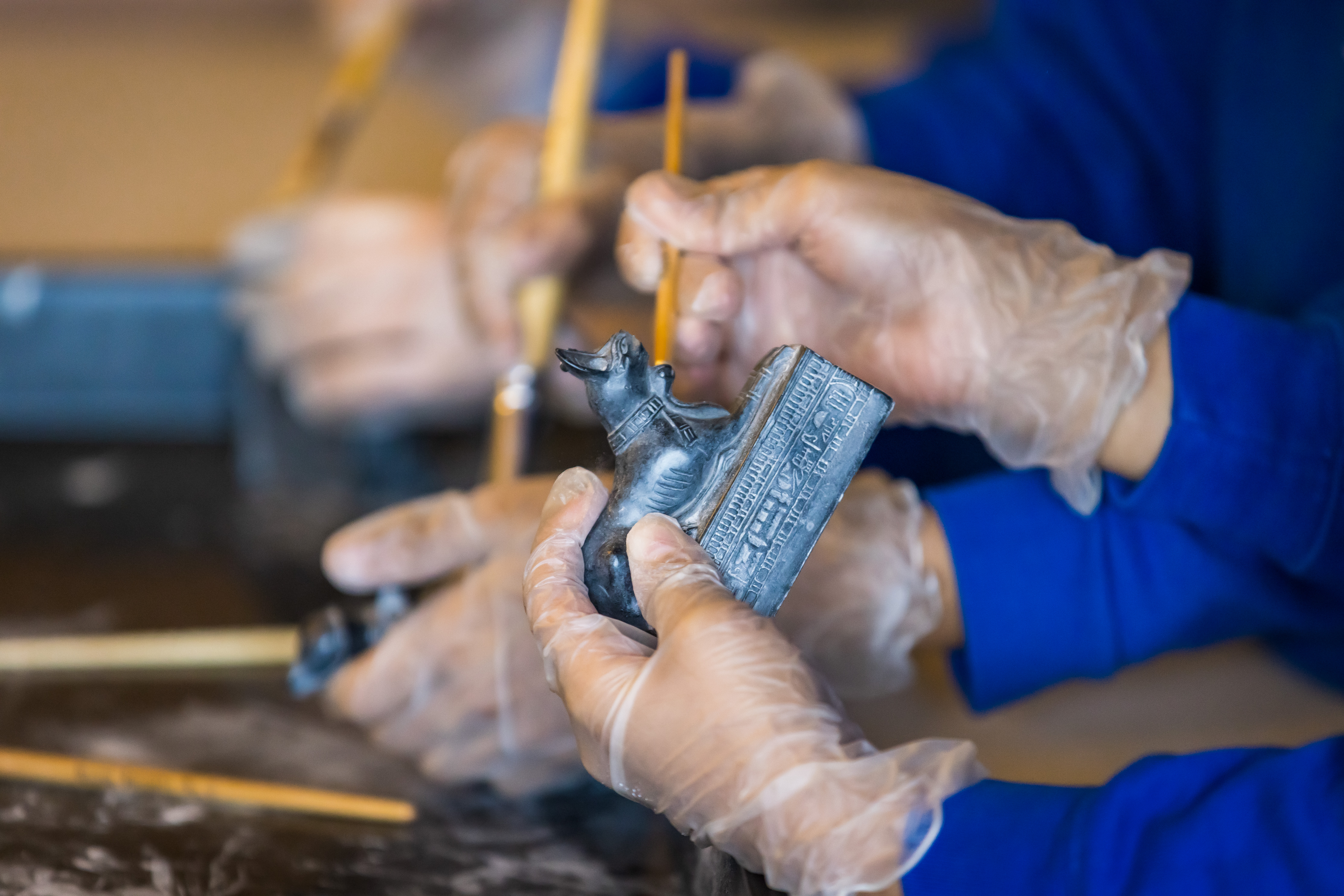 A pair of hands holding an Egyptian artefact