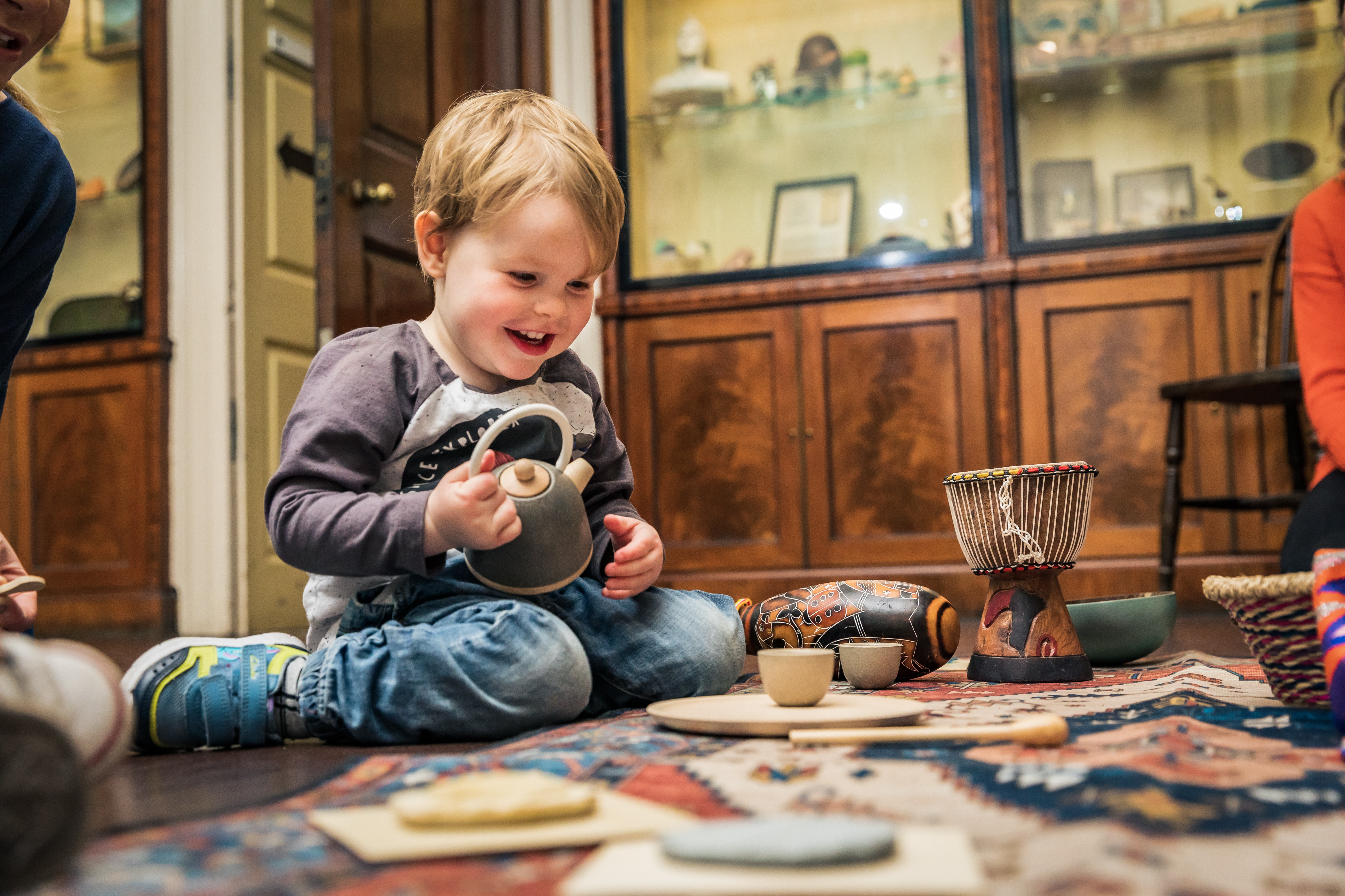 Child sat in the library playing with a toy tea set